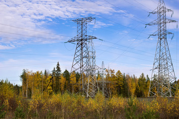 High voltage electric lines and electric poles in a forest autumn