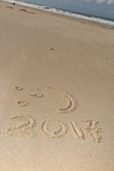 Digits 2017 on the sand seashore - concept of new year