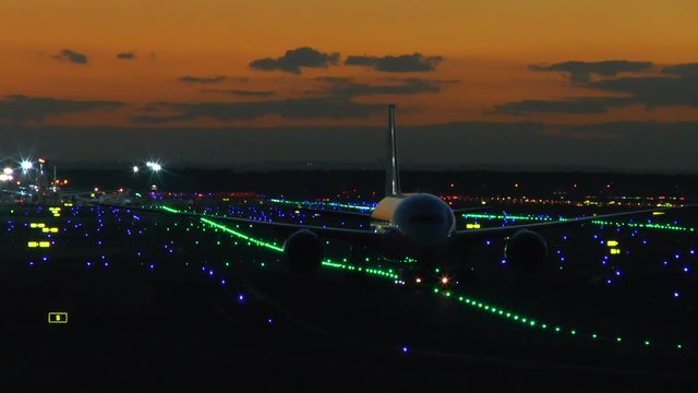 Illuminated airport Frankfurt, Germany - airplanes taxiing and landing on runway