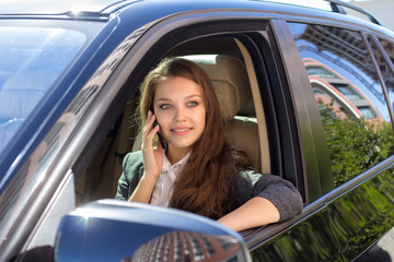 Woman sits in the car and speaks by phone