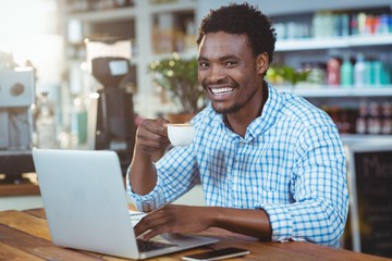 Man using a laptop while having cup of coffee