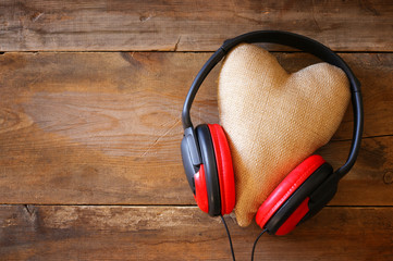 headphones with fabric heart over wooden background