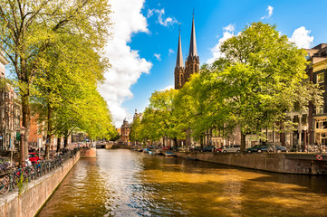 Fototapeta na wymiar Scenic European Amsterdam Canal with church spires on sunny summer day