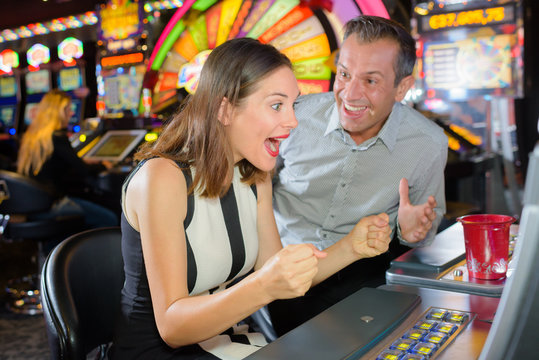 Man and woman winning casino slot machine