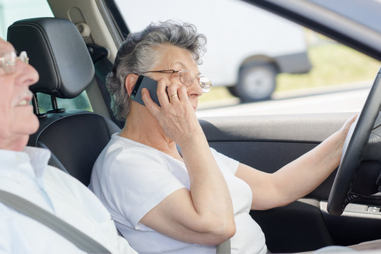 Elderly lady using mobile phone while driving