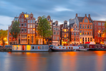 Obraz premium Amsterdam canal Amstel with typical dutch houses and boats during twilight blue hour, Holland, Netherlands.
