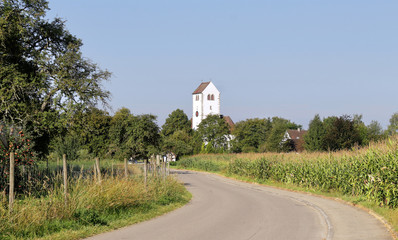 Fototapeta na wymiar Quiet country lane in Germany with white church tower