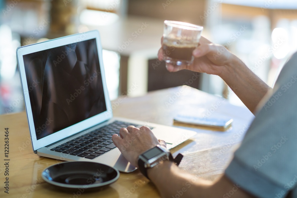 Poster man using a laptop while having cup of coffee