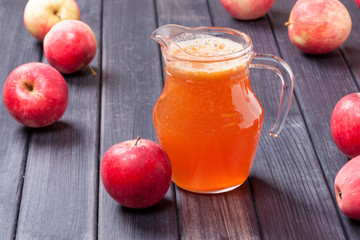 red apples and juice in the pitcher on table