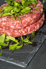 Raw hamburgers with parsley on a stone slate