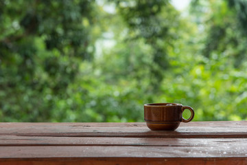 Coffee cup on wooden table with green background