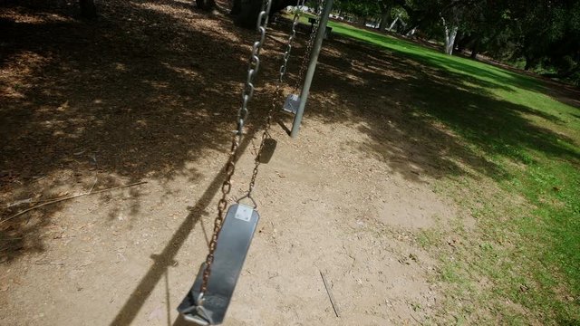 A personal perspective looking at an empty swing set close up.