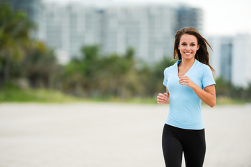 Attractive young female woman running jogging on South Miami Beach Florida with hotels and palm trees in background