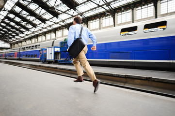 Businessman running late to catch commuter train in big city train railway station