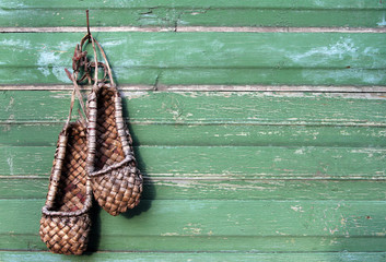 Old bast shoes (traditional russian footwear) on a green wooden