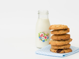 A snack time treat of homemade peanut butter and chocolate cookies and a small bottle of milk on a white, isolated background.