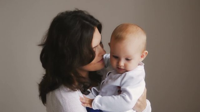 Young Happy Mother Holding her Newborn Child. Family at home. Beautiful smiling Mom and Happy Baby Together.