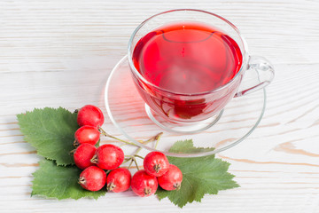 Гроздь боярышника и чашка чая из боярышника на деревянном фоне
