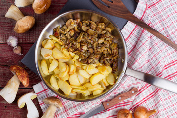 Fried potatoes with cepes in a steel frying pan on the table