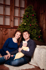 a young family with a baby near Christmas tree