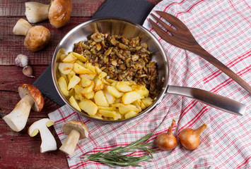 Fried potatoes with cepes in a steel frying pan on the table