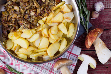 Fried potatoes with cepes in a steel frying pan on the table