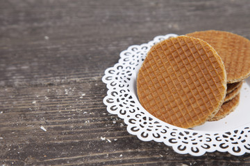 Dutch cookie stroopwafels on white plate on brown wooden background