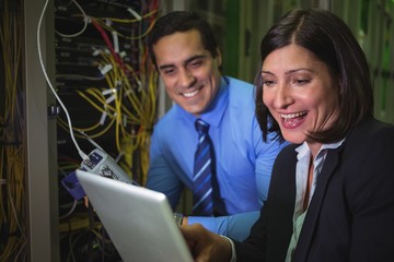 Technicians using digital tablet while analyzing server