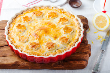 Cherry pie in a baking dish on a cutting wooden board background