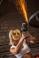 Mechanic woman in sexy uniform is working with the sander.