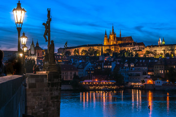 Naklejka na ściany i meble Stunning view of the illuminated Prague just after sunset. The Castle Complex, from the Charles bridge