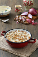 zuppa di pasta e ceci in tegame di metallo sfondo tavolo di cucina rustico