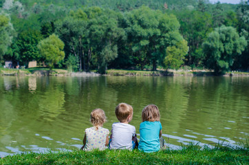 Three friends are sitting on the shore of the lake