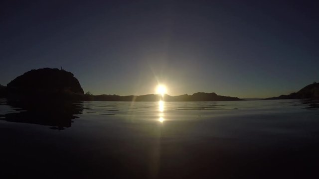 A wide angle POV floating in a lake at sunset.