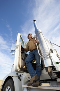 A Man Standing On The Step Of The Cab Of His Truck, Three Hills, Alberta, Canada