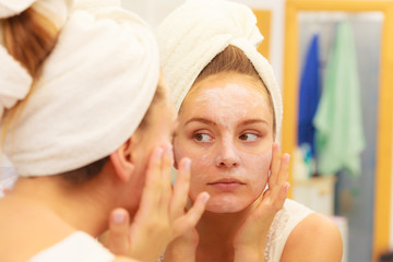 Obraz na płótnie Canvas Woman applying mask cream on face in bathroom
