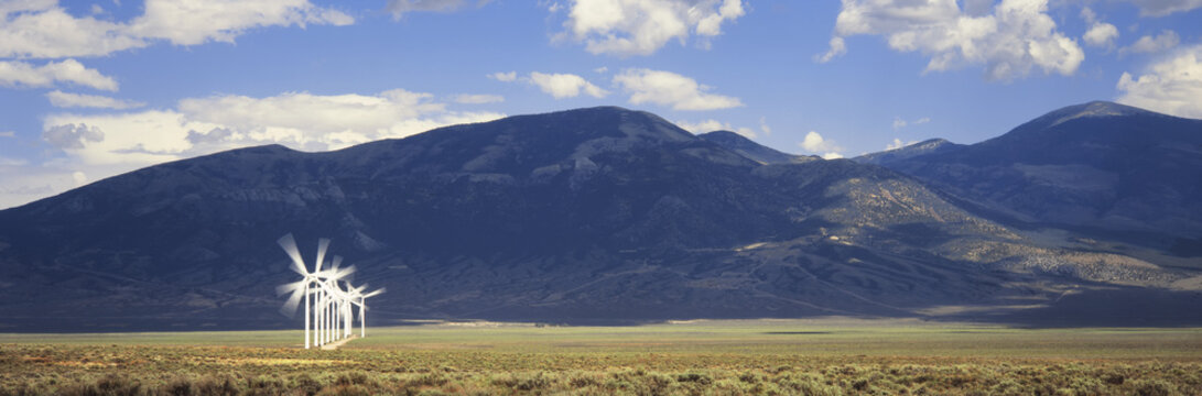 Single row of wind generators with mountains beyond, near Milford, Utah, United States of America