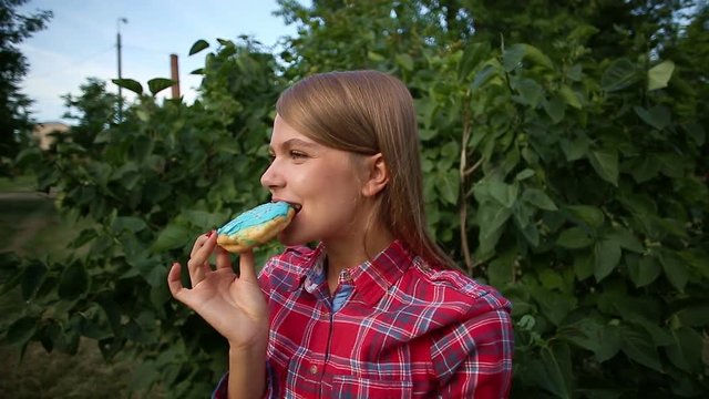 Young girl eating a donut in the park. Enjoying the sweetness. Sweet life.