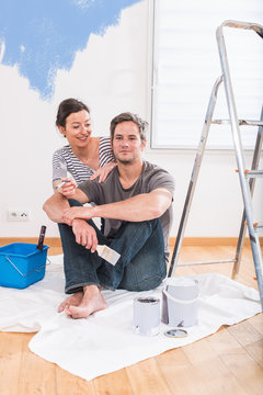 Handsome couple painting walls of their new home