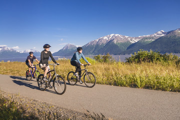 Two women and a man biking on the bird point to girdwood bike trail, turnagain arm;Anchorage, alaska, united states of america