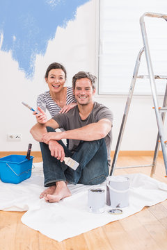 Handsome couple painting walls of their new home