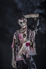 Male zombie standing on black background, looking at camera. Halloween theme
