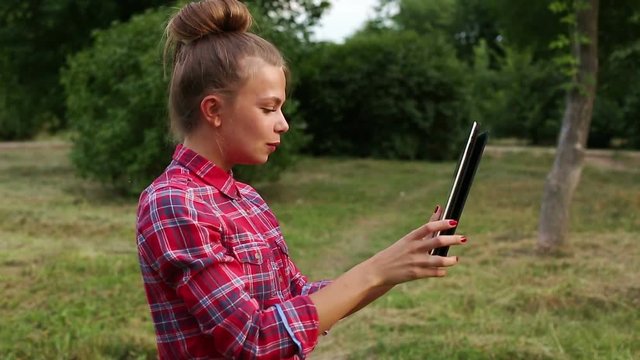 Young attractive woman uses a Tablet PC as a mirror. She responds to messages in social networks.