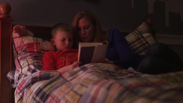A mother reading her son a book before bed