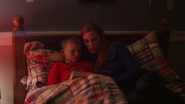 A mother reading her son a book before bed