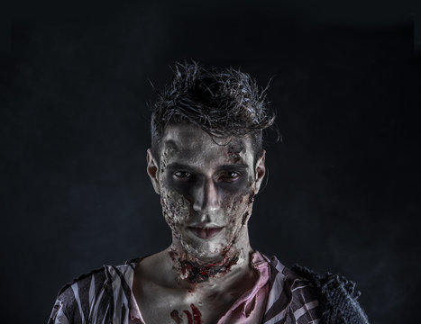 Male zombie standing on black background, turning around looking at camera. Halloween theme