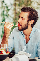 handsome young man sitting in a cafe and eat watermelon