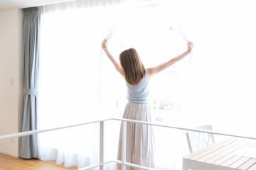 カーテンを開ける女性