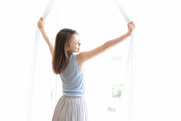 カーテンを開ける女性