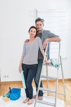  a cheerful couple prepares to wallpapering his new apartment